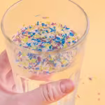 A glass of water containing beads of plastic ,plastic droplets