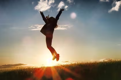 Silhouette of a person jumping over a horizon, signifying their joy at achieving more business success by developing more future-ready skills