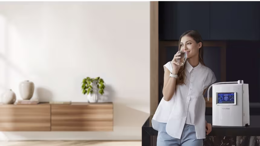 Woman standing next to homepure viva drinking water in kitchen