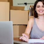Girl smiling in front of boxes for her micro, small and medium-sized enterprise