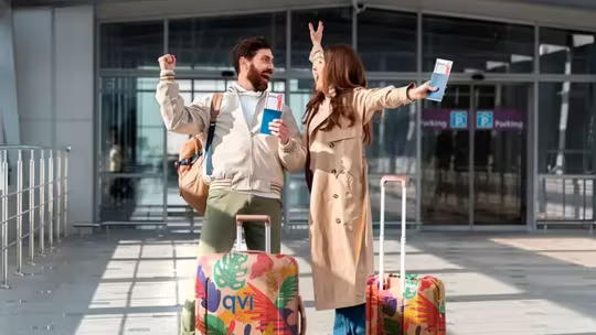 Why Membership Travel Might Be The Smartest Way To Book Your Next Trip 2 couple outside airport cheering with their luggage